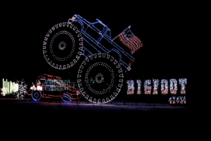 Large christmas light display with a monster truck and a sign that reads bigfoot