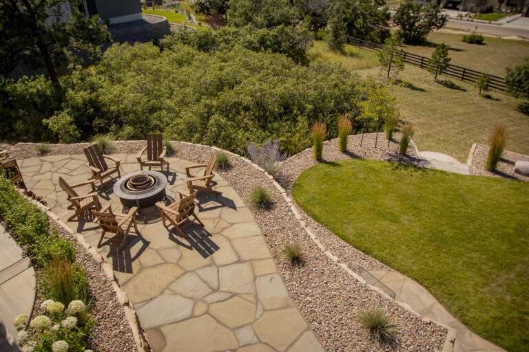 Flagstone patio with xeriscaping and firepit with chairs.