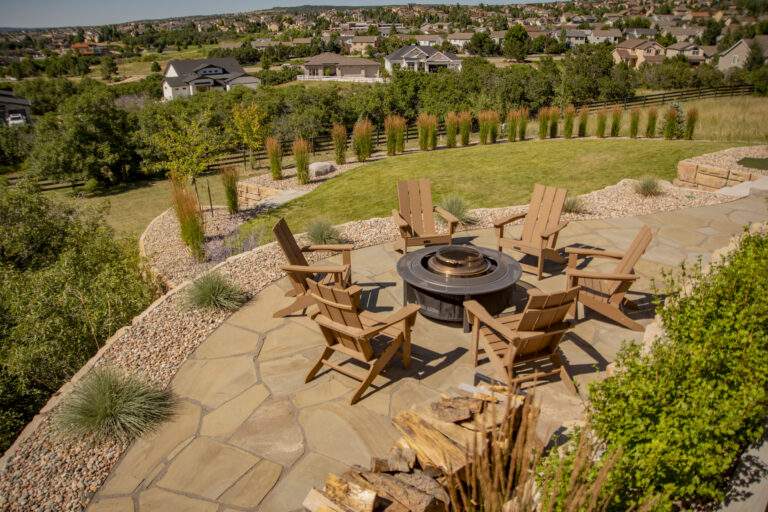 Flagstone patio with xeriscaping and firepit with chairs.