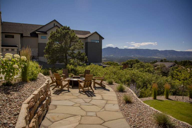 Flagstone patio with xeriscaping and firepit with chairs.