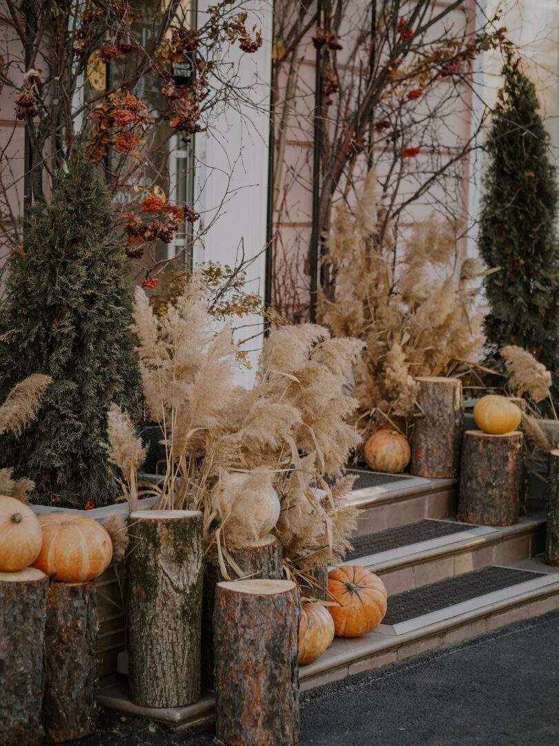 fall outdoor décor - Rustic fall front door with cut logs, pumpkins tried grasses